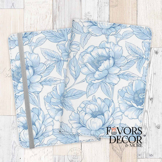 Passport cover with blue floral line art in toile style on white background, displayed on wood surface.