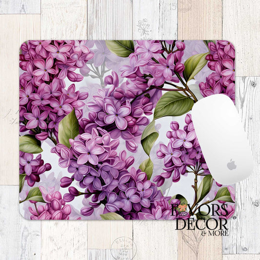 Mouse pad featuring blush and violet lilacs with green leaves on a light background, styled with a white Apple mouse and “Favors Decor &amp; More” branding.