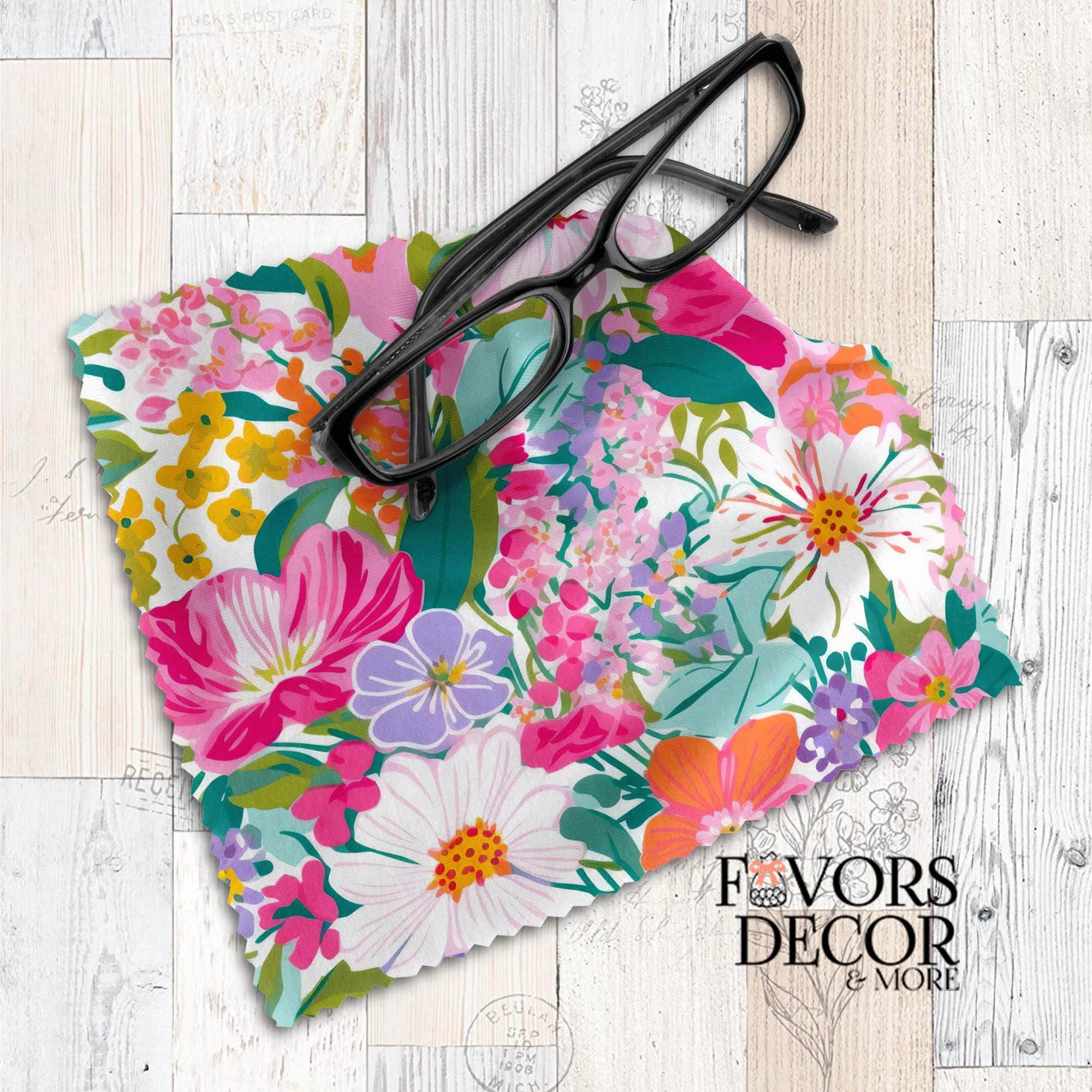 Colorful floral lens cloth featuring vivid pink, yellow, orange, purple, and white blooms on a white background, styled with black eyeglasses.