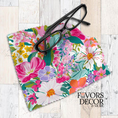 Colorful floral lens cloth featuring vivid pink, yellow, orange, purple, and white blooms on a white background, styled with black eyeglasses.