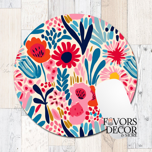 Round mouse pad with abstract floral and leaf shapes in red, blue, yellow, black, and blush on a cream background, featuring a smooth fabric surface and non-slip rubber backing.