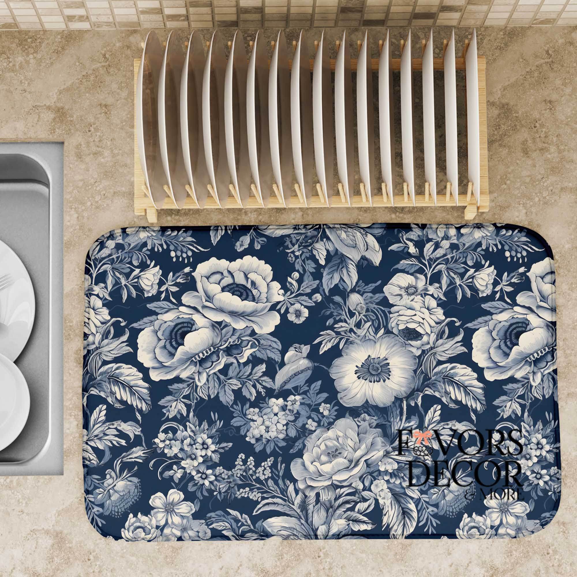 Navy and white floral dish drying mat on a kitchen countertop with a wooden dish rack and plates nearby.
