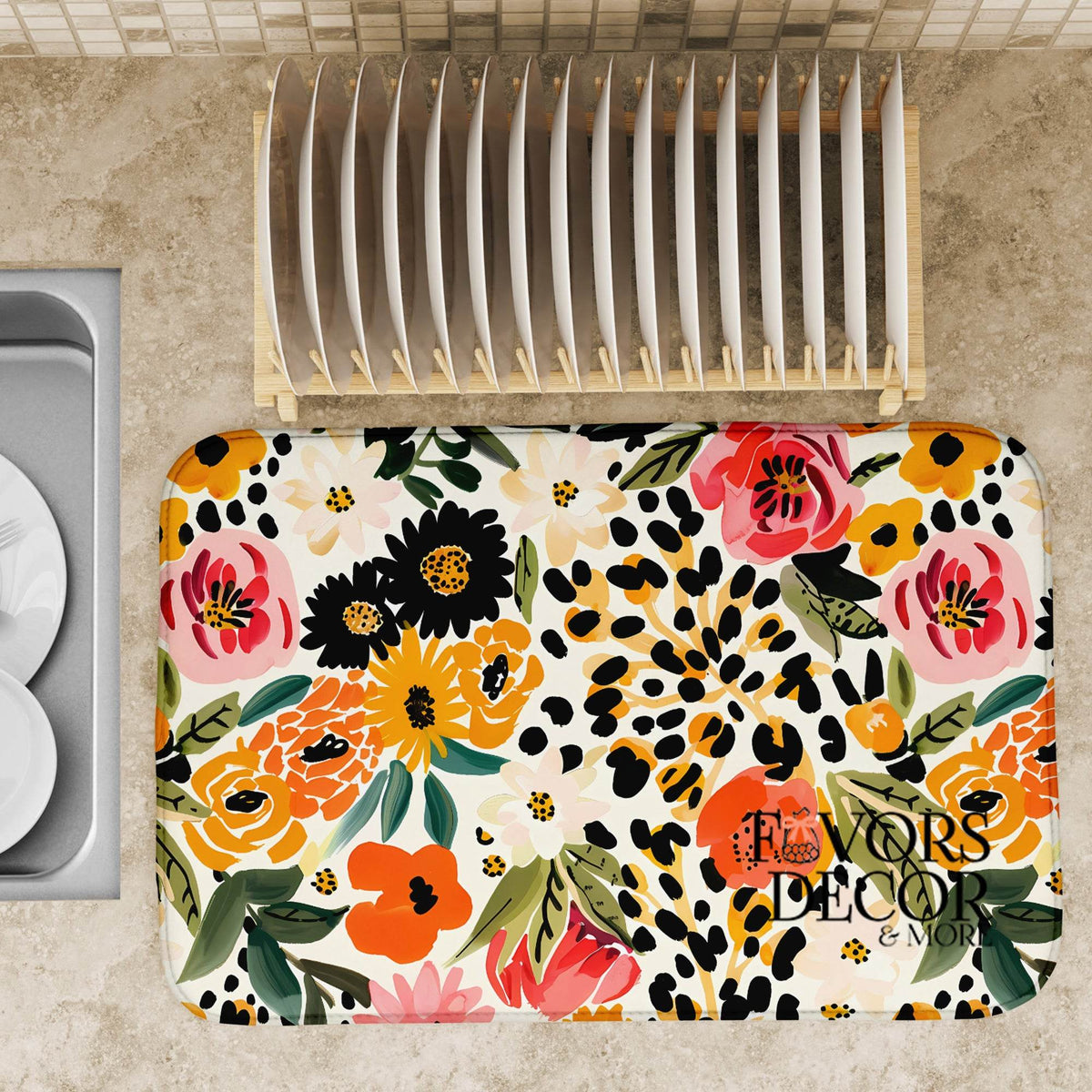 Dish drying mat with colorful floral and leopard print design on a kitchen countertop next to a dish rack.