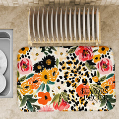 Dish drying mat with colorful floral and leopard print design on a kitchen countertop next to a dish rack.