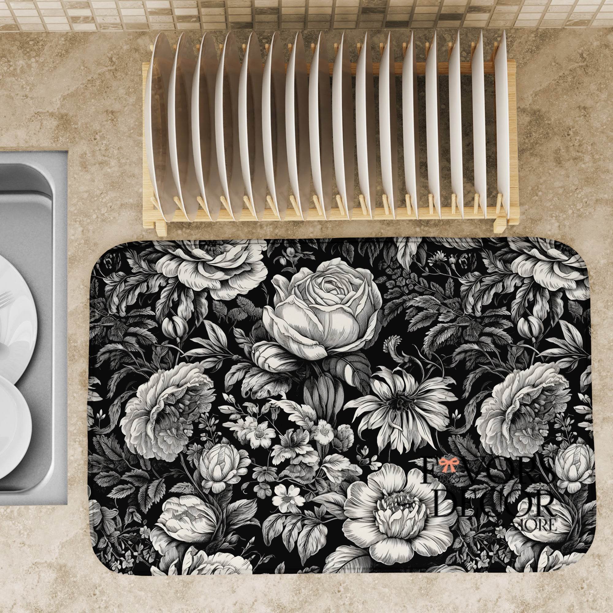 Black and white floral dish drying mat on a kitchen counter, styled with a wooden dish rack and elegant dinnerware.