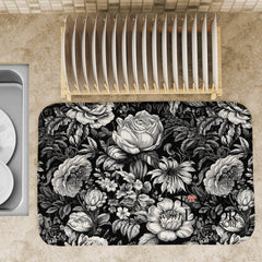 Black and white floral dish drying mat on a kitchen counter, styled with a wooden dish rack and elegant dinnerware.