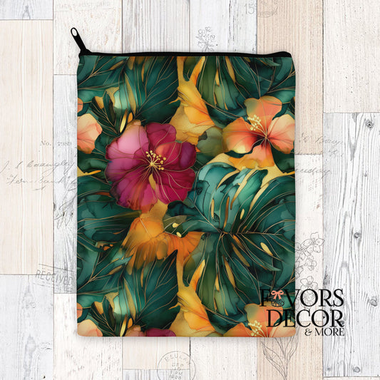 Book sleeve with emerald monstera leaves and colorful alcohol ink florals in red, orange, and gold, zippered top, styled on light wood background