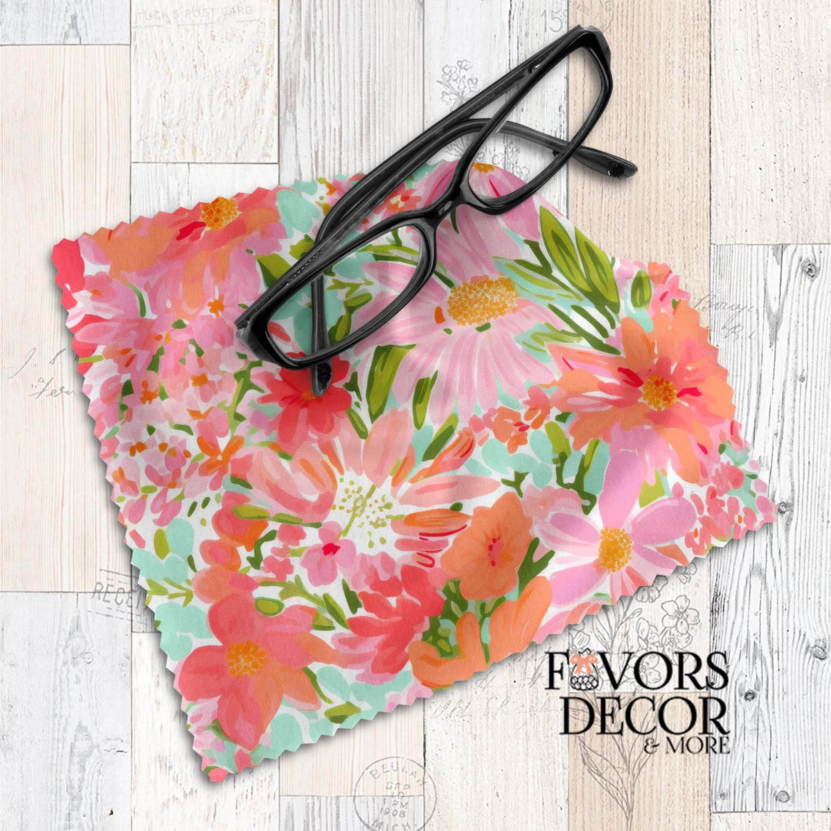 Floral lens cloth with bright pink, coral, peach, and green flowers in a watercolor style, styled with black eyeglasses.