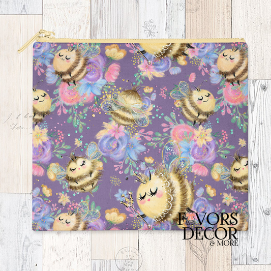 A reusable sandwich pouch with a purple background and a whimsical pattern of sleeping bees with eyelashes, surrounded by colorful pastel flowers and subtle honeycomb details. The pouch has a gold zipper closure.