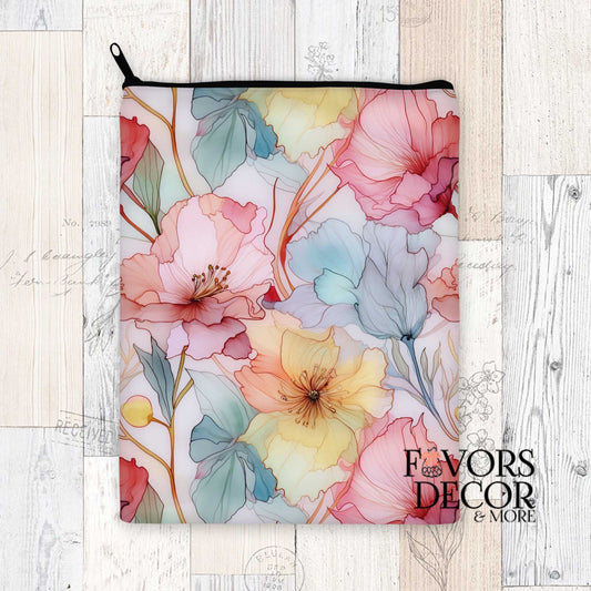 Book sleeve with pastel alcohol ink floral print in pink, yellow, lavender, and teal, zippered top, styled on light wood background